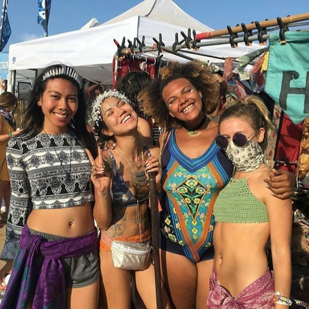 Four joyful young women at a festival booth, full of color and laughter.